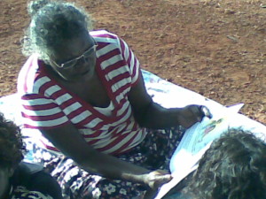 Nami reads a book about fighting to the children during a group session on the beach.